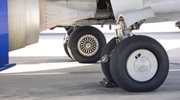 Close-up of the tires and landing gear of a commercial aircraft on a tarmac. 