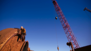 Industrial miner using rope access fitters working at height with a safety harness. 
