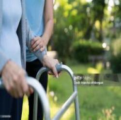 Elderly person with a walker assisted by caregiver