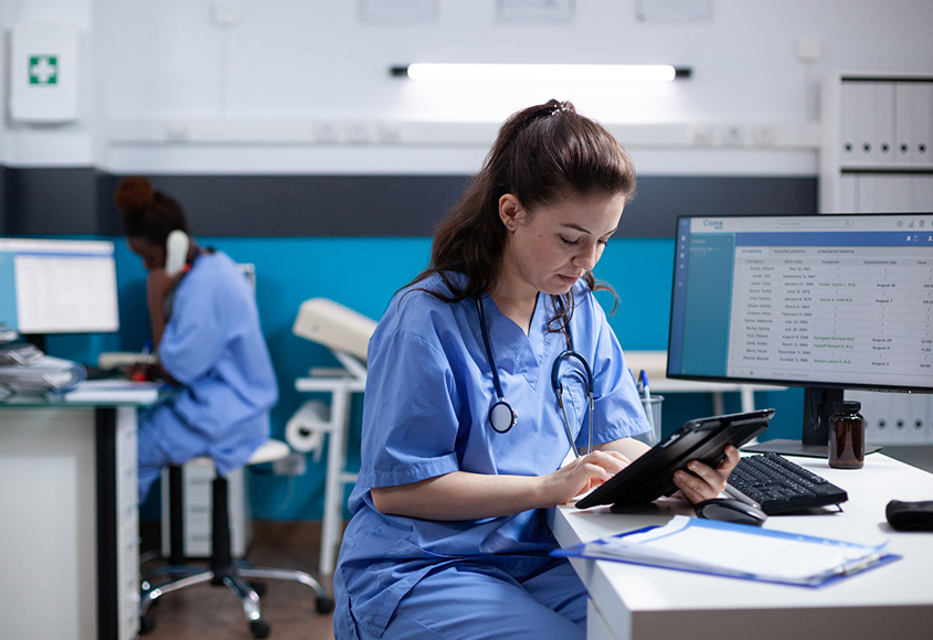Women in medical scrubs looking at tablet computer.