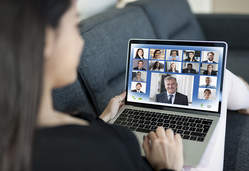 Woman on couch having a zoom meeting.