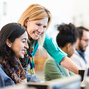 Two people looking at computer screen and smiling.