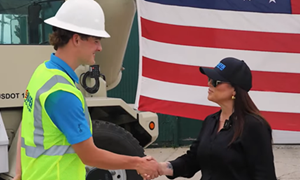 Secretary Chavez-DeRemer shakes the hand of a young male worker wearing a hard hat and high visibility vest.