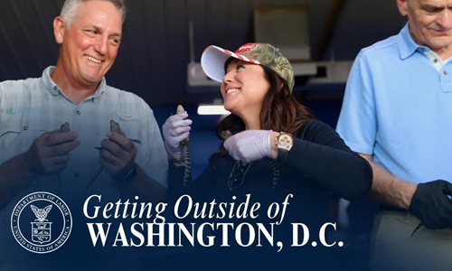 Secretary Chavez-DeRemer holds a baby alligator and smiles while standing next to the business owner