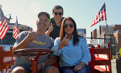 Secretary Chavez-DeRemer and Deputy Secretary Sonderling give a thumbs up while sitting on a red vintage truck with a member of the Teamsters