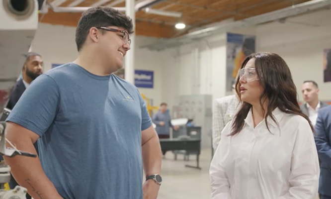 Secretary Chavez-DeRemer holds a baby alligator and smiles while standing next to the business owner
