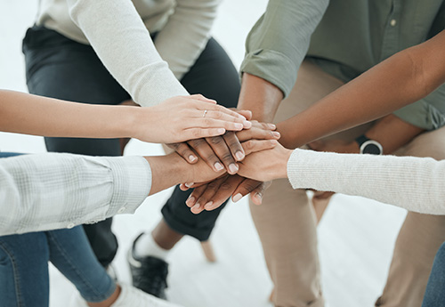 six people putting their hands together in a circle.