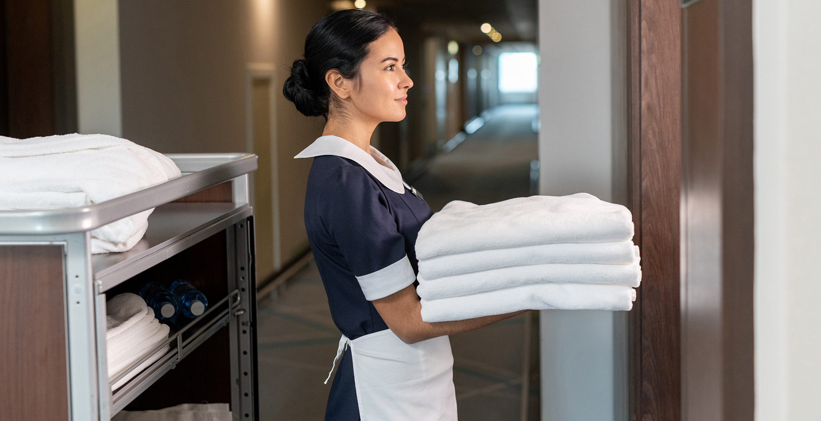 Una empleada de hotel entregando sábanas a una habitación