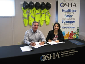 Lee Lewis, chief executive officer with Lee Lewis Construction Co., signs OSHA alliance agreement with Elizabeth L. Routh, OSHA's area director in Lubbock, Texas.
