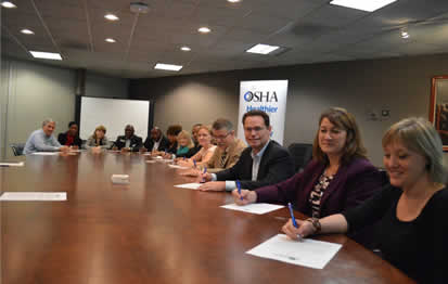 Eileen O'Laughlin, program manager, Georgia Department of Economic Development; Christi Griffin, OSHA's Atlanta-West area director; and Scott Shelar, executive director, Construction Education Foundation of Georgia; and other alliance members signing the renewal agreement.