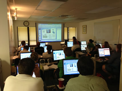 Image of a group of employees sitting at computers in a training class