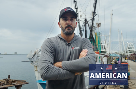 person with arms crossed standing on a shrimp boat