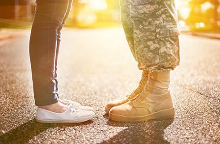 View of two people's feet facing each other, one dresses as civilian, the other in military clothing