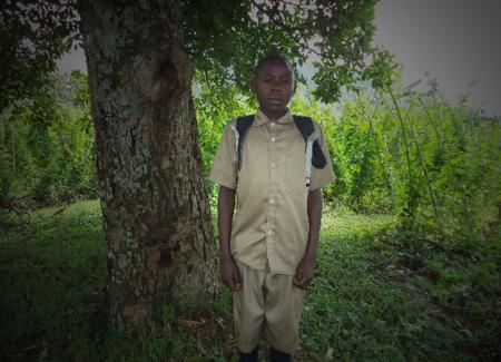 Habimana stands in front of a tree. Photo by Winrock International.